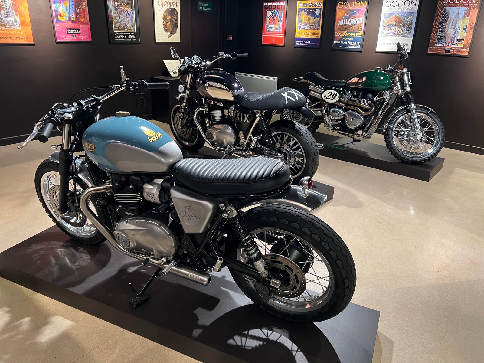 GODON BIO exhibition view: motorcycles displayed beneath a wall of Alain Godon's posters