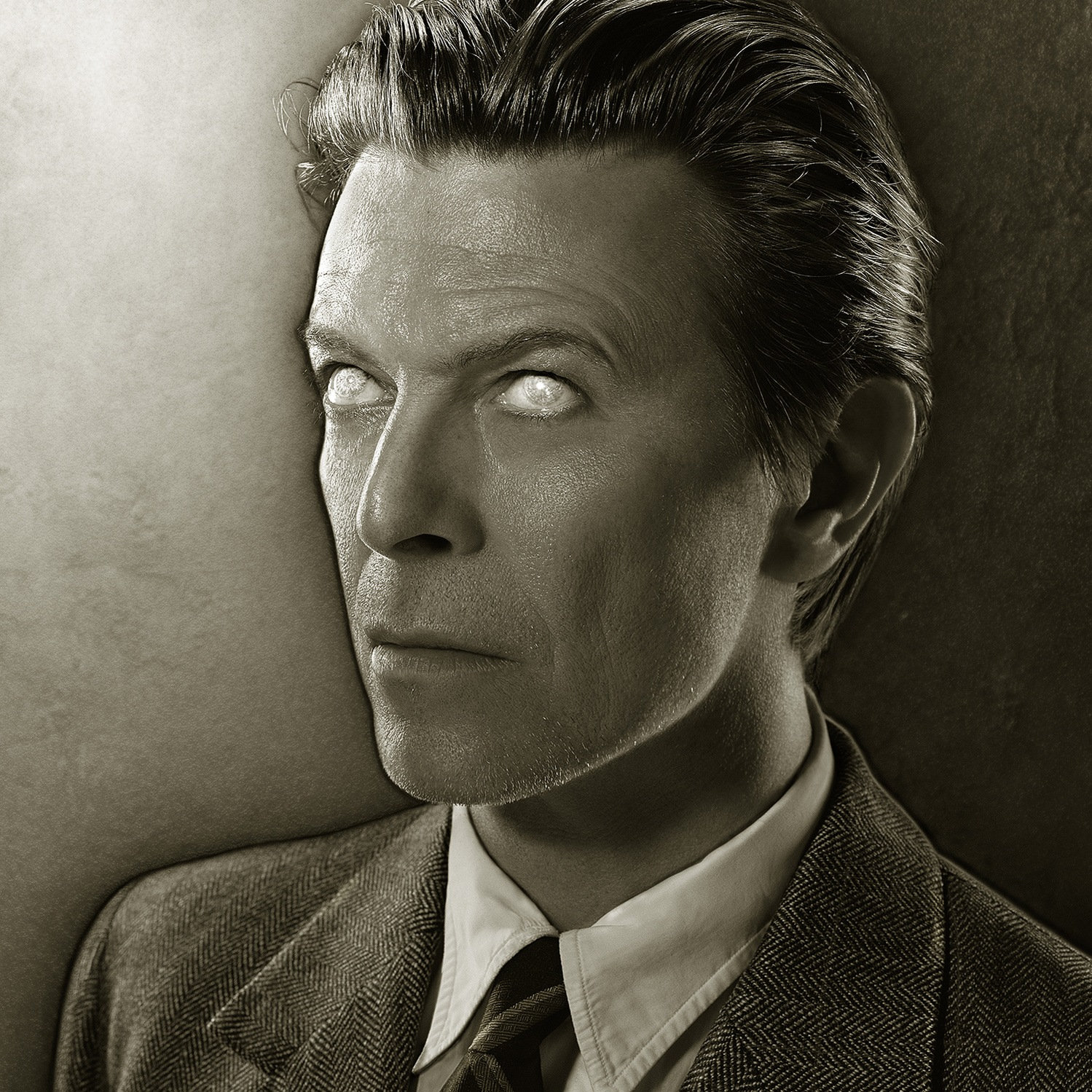 Sepia portrait of David Bowie in a suit and tie, head turned to the side, his eyes rendered blank and white.