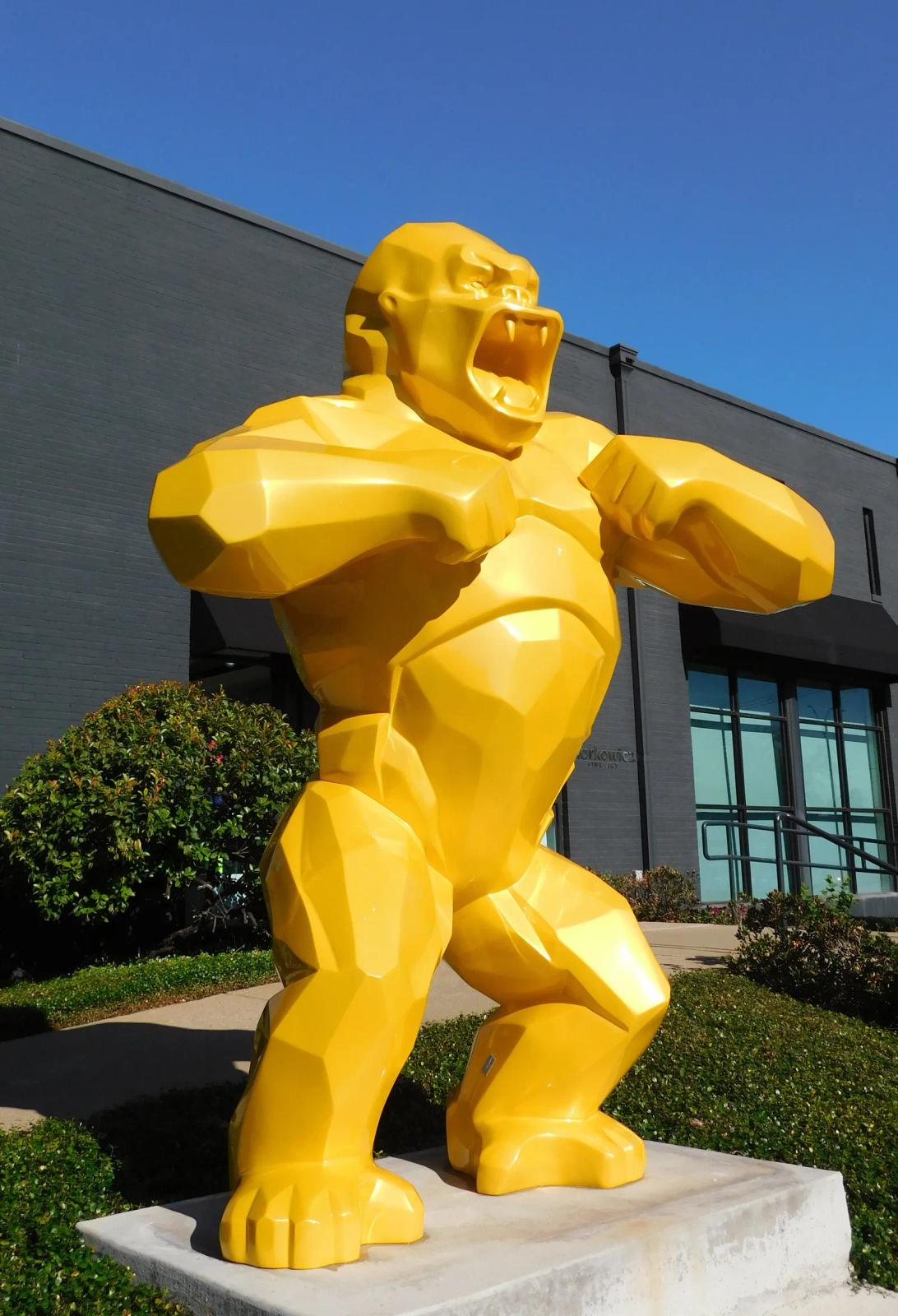 Yellow faceted Wild Kong sculpture by Richard Orlinski standing in front of the Markowicz Fine Art gallery in Dallas under a blue sky